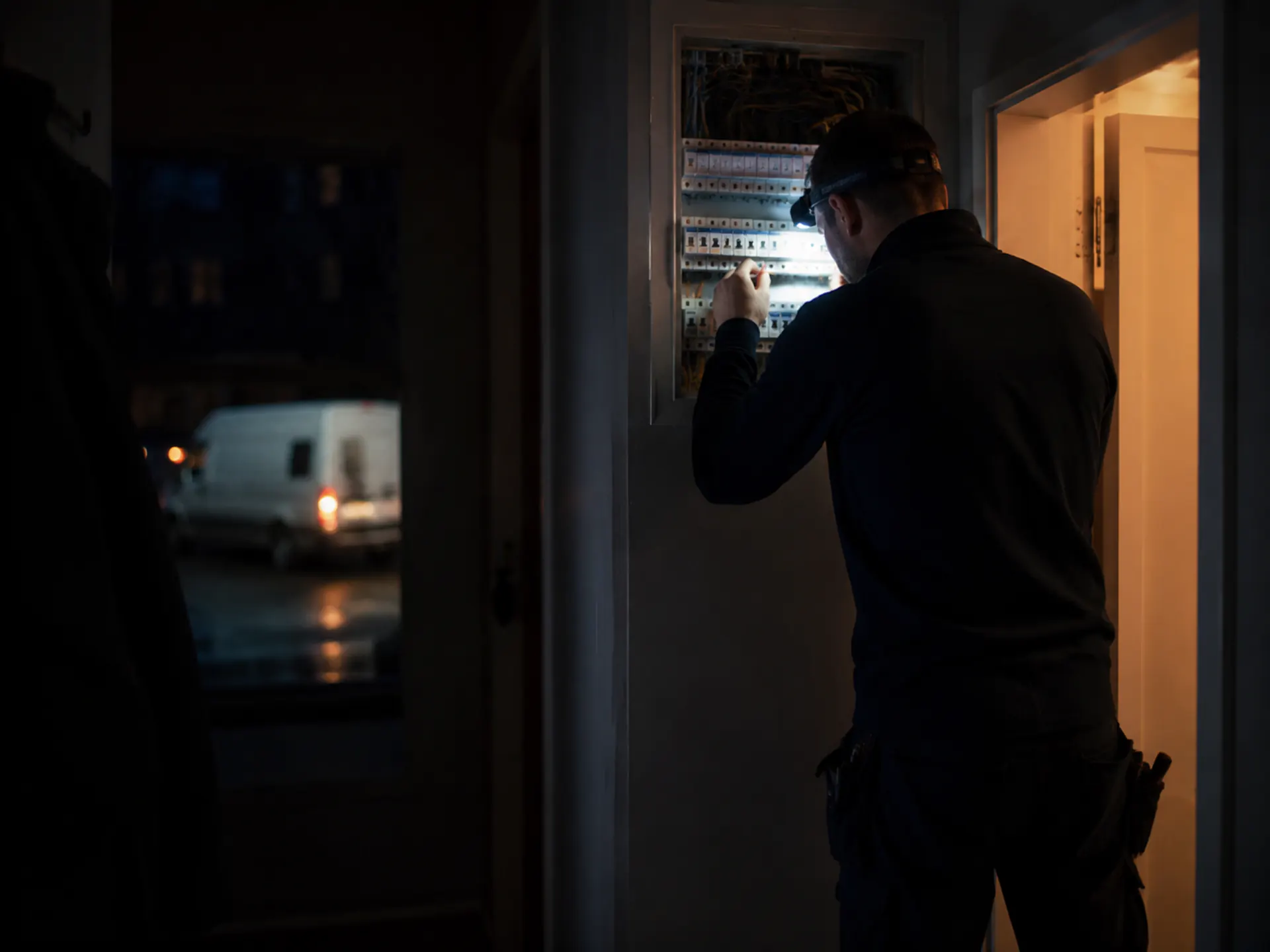Elektricien van Sigelekt herstelt 's avonds een verdeelbord na stroomuitval, met zaklamp en meettoestel