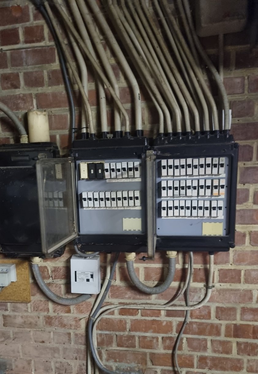 Twee oude bakelieten verdeelkasten op een bakstenen keldermuur in Kampenhout, vóór